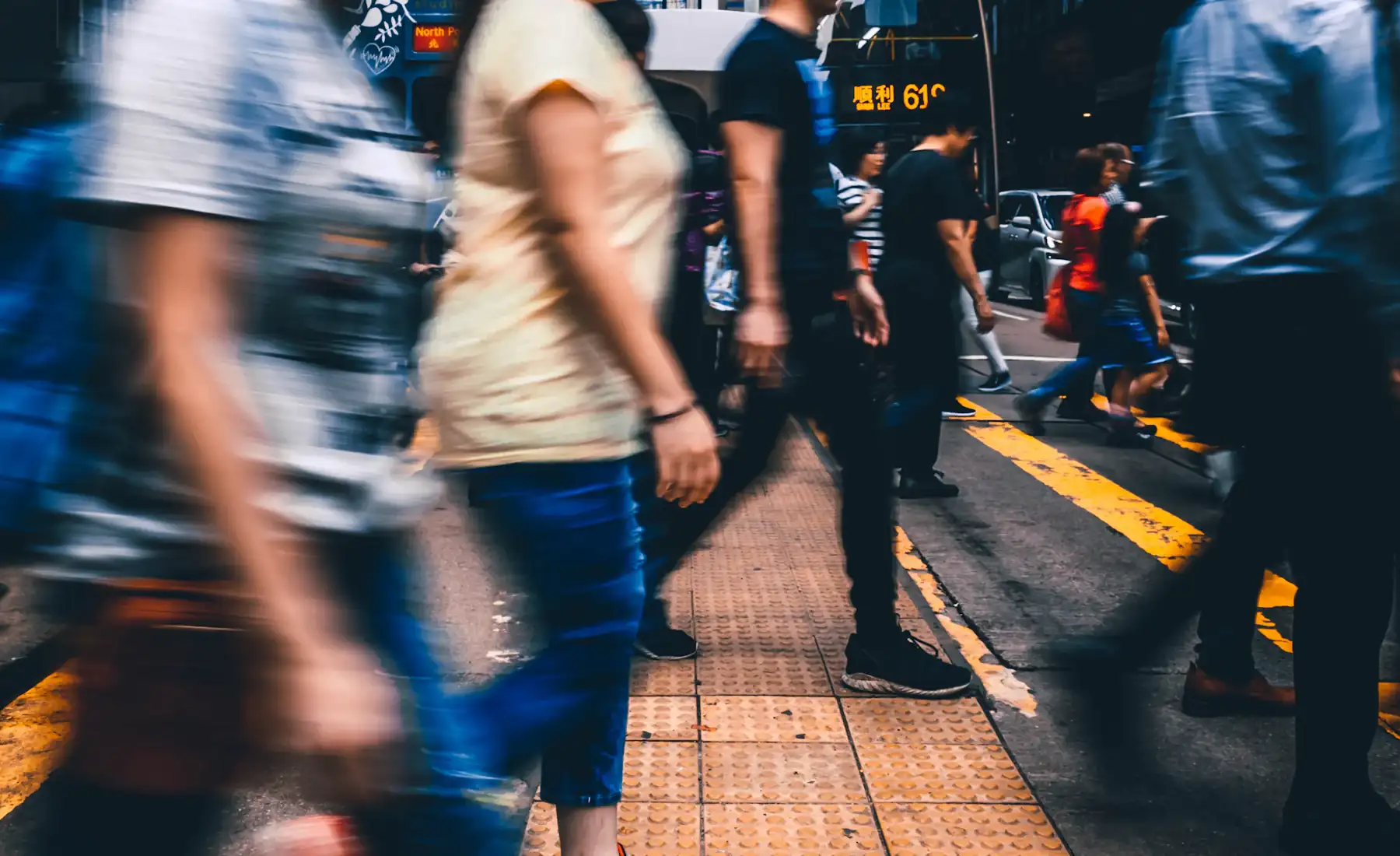 People crossing a busy city street between tall buildings